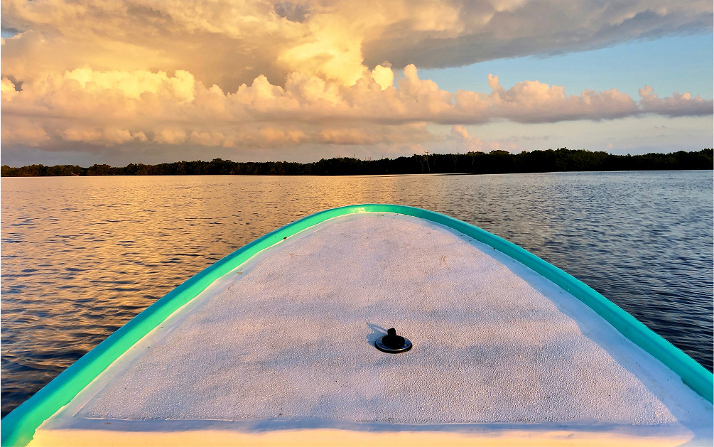 Front of boat with waters and sky in background.
